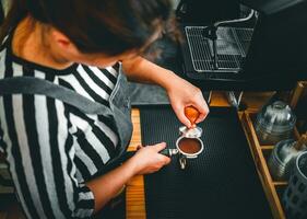 Barista holding portafilter and coffee tamper making an espresso coffee in cafe photo