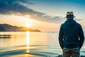 a man in a hat and jacket stands on the shore at sunset. AI-Generated photo
