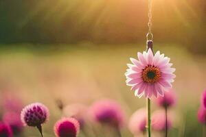 a pink flower is hanging from a string in a field. AI-Generated photo