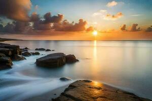 un hermosa puesta de sol terminado el Oceano con rocas y agua. generado por ai foto