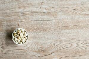 nuts in a cup on an old wood grain table Left corner and take a closeup and top view, has copyspace for text input, the photo is a landscape
