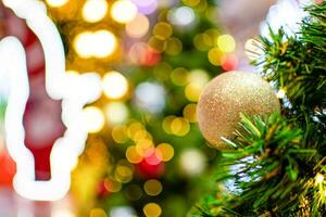 Closeup large golden balls on a Christmas tree decorated 2020 with small bulbs are beautiful. Copy space and beautiful bokeh on left for design or text, blurred background. photo