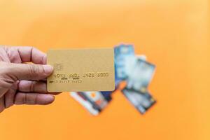 Businessman showing debit card online shopping, payment, online banking, money transfer, concept, selective focus, copy space, right. Closeup, man's hand holding credit card on orange, blur background photo