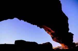 a large rock arch in the desert at dusk photo