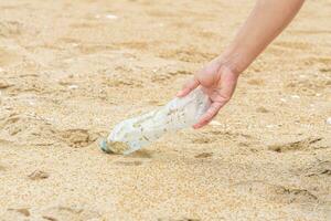 Woman cleans up by picking up plastic bottles at beach. Concept of protecting the environment, saving the world, recycling, reducing global warming. closeup, blurred background, World Environment Day photo