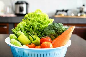 Close-up, Cucumbers, lettuce, carrots in blue containers were placed on a wooden table. These vegetables are for making healthy meals. Blurred background. photo