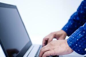 Closeup, People work home blogger. A man standing and typing with a keyboard notebook computer on a white desk in the living room at home. The screen is a blank, White blurred background, Copy space photo