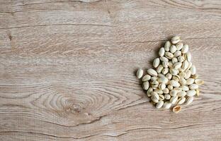 many white nuts on a right old wood grain table corner and take a closeup and top view. left copy space for text input, the photo is a landscape