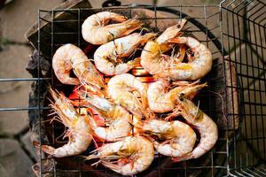 Seafood, Grilled shrimps on the cinder flaming grill and no smoke. The photo is a top view and takes a closeup. Shrimp has an orange color, is heated by a fire.