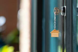 House key with house keyring in the keyhole on the glass door. The concept for purchasing real estate, construction, housing, condominium, buying, and selling. Close-up. copy space. blurred background photo