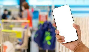 A man's hand holds a smartphone screen white and blank in a supermarket. Concept of financial transactions with mobile devices. Closeup, money, transfer, online, payment, internet. blurred background photo