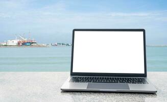 Blank white screen laptops are placed on a marble desk outdoor. The Concept for business, technology, internet, design, and programmer. Copy space on left. Closeup, selective focus, blurred background photo