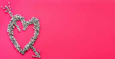 Heart symbol and arrow made of small stones Or pebbles placed on a pink background. It is a concept of love day or Valentine's day. Take a top view and close-up photo