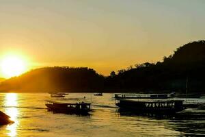 boats on the river at sunset with mountains in the background photo