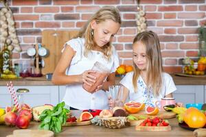 Two little girls in the kitchen with fresh vegetables. Healthy food concept. Happy sisters. photo