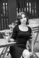 Beautiful young woman drinking white wine on the terrace of a restaurant. Relaxing after work with a glass of wine. Single woman having fun. photo