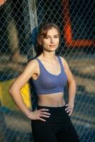 Sporty young woman in sportswear doing stretching exercises outdoors. Portrait of a young girl doing sport in the park. photo