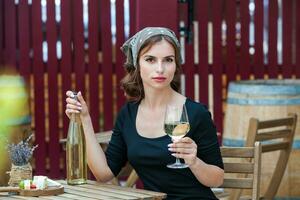 hermosa joven mujer Bebiendo blanco vino en el terraza de un restaurante. relajante después trabajo con un vaso de vino. soltero mujer teniendo divertida. foto