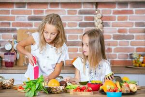 Two little girls in the kitchen with fresh vegetables. Healthy food concept. Happy sisters. photo