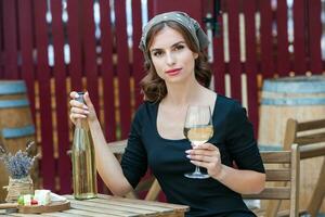 hermosa joven mujer Bebiendo blanco vino en el terraza de un restaurante. relajante después trabajo con un vaso de vino. soltero mujer teniendo divertida. foto