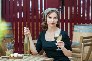 Beautiful young woman drinking white wine on the terrace of a restaurant. Relaxing after work with a glass of wine. Single woman having fun. photo