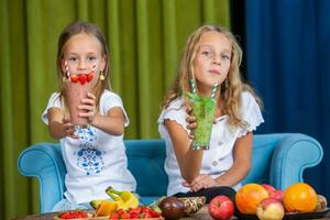 Two little girls in the kitchen with fresh vegetables. Healthy food concept.. Happy sisters photo