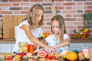 Two little girls in the kitchen with fresh vegetables. Healthy food concept. Happy sisters. photo