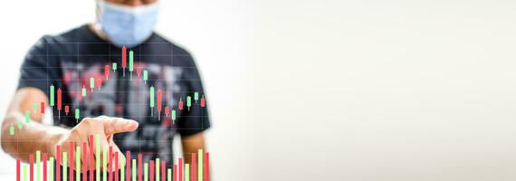 A man wearing a coronavirus face mask, or COVID-19, is pointing his finger at a color graph showing market activity on the holidays. Take a close-up photo landscape with a white and blurred background