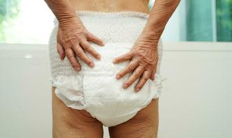 Asian senior woman patient wearing adult incontinence diaper pad in hospital. photo