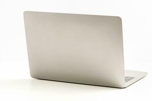 The back of the laptop is blank, placed on a white desk in an office, and nobody. Technology work concept, smartphone, notebook, internet, left side copy space, close up, white background, and blurred photo