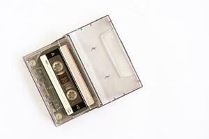 A tape in a cassette which is technology from the 90s, used for recording music or sounds, is placed on a white table, close-up, selective focused, white background. copy space on right for a design photo