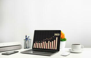 Laptop is graph displayed on the desk in the office and has Smartphone, and coffee cup. The concept of business, finance, banking, and interest is booming. Copy space on top for design, Closeup, 202 photo