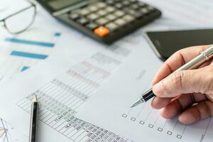 professional businessperson man hand holding pen and checking list report information data document or paperwork business of banking finance accounting on desk office for management investment stock photo