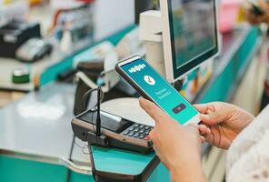 woman hand holds a smartphone on screen with message Payment Successful in a supermarket. Concept of financial transactions with mobile devices. Closeup, money, transfer, online. blurred background photo