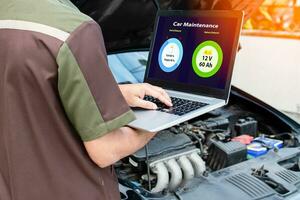 Closeup, man's hand typing on laptop computer keyboard to check the operation of the car engine in the garage. The engine of a car does not start. Notebook computer screen shows battery and oil status photo