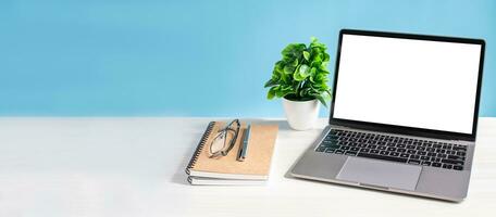 Blank and white screen laptop on a wooden table in the office. Working concept using technology, notebook, internet, laptop computer, network. Copy space on left for design, Closeup, blue background photo