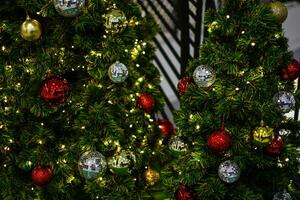 el verde Navidad árbol decorado con pequeño bombillas es un hermosa Bokeh. Navidad árbol decoración con blanco, rojo, dorado pelotas, de cerca un foto, Copiar espacio en Derecha para diseño, borroso antecedentes. foto