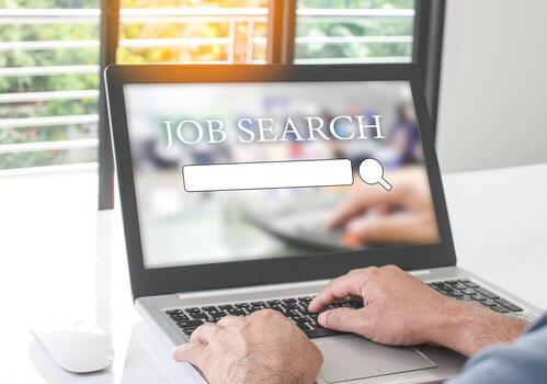 A man sits and typing keyboard to job search in the work at home. Find work with a laptop computer and put it on the white table in living room. Concept of business service survey. Blurred background photo