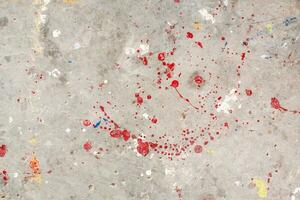 The floor is stained with several drops of various colors. Dripping paint on the concrete floor beautiful art. Droplets of red, black, and white stains on the ground. Multiple oil paint on background. photo