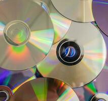 Many old CDs represent technology from the 90s. Stacks of CDs, old songs and old movies. which had been used before and placed on a white table. closeup, selective focus photo