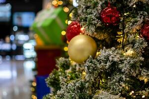 Close up medium golden balls Christmas tree decorated with small bulbs is beautiful. Christmas tree decoration with white snow, copy space on left for design or text, blur background, beautiful bokeh. photo
