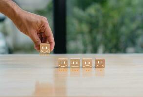 a hand is holding a wooden block with smiley faces on it photo