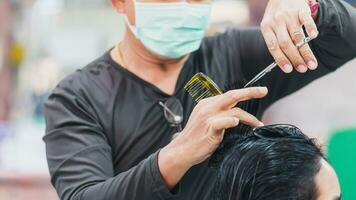 professional man hairdresser wearing face mask holding scissors and haircutting client woman indoor salon, man make business hair care has tool haircut to service haircut to customer, selective focus photo