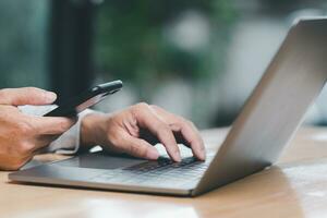 Man uses his finger to press button to turn off, closed, shut down laptop computer placed on desk, is time to finish each day before going home for saving energy. After saving all data business work. photo