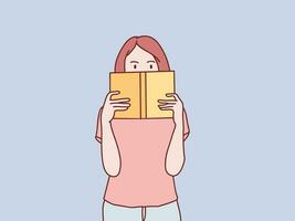 young girl reading hiding behind an open book vector