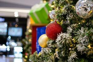 Closeup medium red balls Christmas tree decorated with small bulbs is beautiful. Christmas tree decoration with white snow, copy space on left for design or text, blurred background, beautiful bokeh. photo