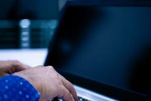 Close-up, A people work home blogger. A man sitting and typing with a keyboard notebook computer on a white desk in the living room at home. The screen is a blank, Blurred background, Copy space photo