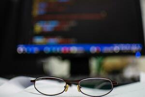 Programmer's glasses put on the document to relax after long coding for application creation and website design for businesses with a focus on cybersecurity. tack closeup photo and blurred background