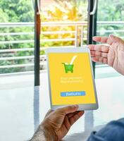 The tablet screen displays a Your payment Was successful message to confirm payment is complete for online shopping. Man sit and holding tablet. Concept of shopping with a tablet. Blurred background photo