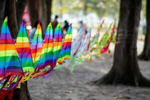 Selective focus kites. Beautiful colorful kites Hanging together at the beach by the sea for sale to tourists. who come to visit in the evening when the wind blows. Close-up, blurred background. photo